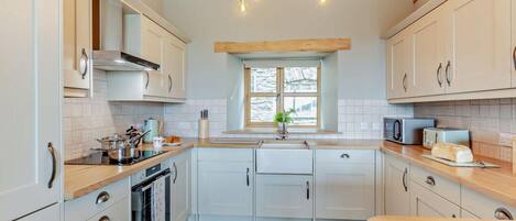 A modern kitchen with light-colored cabinets, a central island, and a built-in oven.