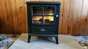 A black wood-burning stove with a glass door, set against a wooden wall. - 3 Bed in Kendal (oc-sz466) (Longsleddale)