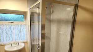 A bathroom with a glass shower enclosure, a sink, and a window with a floral curtain. - 3 Bed in Kendal (oc-sz466) (Longsleddale)