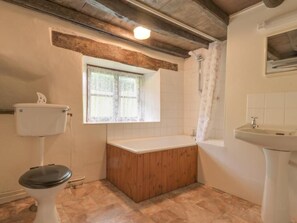 Une salle de bain avec des toilettes, une baignoire en bois et un lavabo.