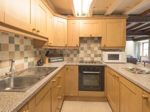 A kitchen with wooden cabinets, a microwave, a toaster, and a sink. - 4 Bed in Kendal (oc-sz100) (Longsleddale)