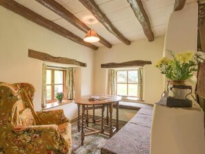 A room with a wooden ceiling, a round table, a floral armchair, and a window with a view. - 4 Bed in Kendal (oc-sz100) (Longsleddale)