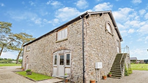 A stone building with a door, windows, and a staircase leading to a second floor. - 1 Bed in Bucknell (oc-94661) (Letton)
