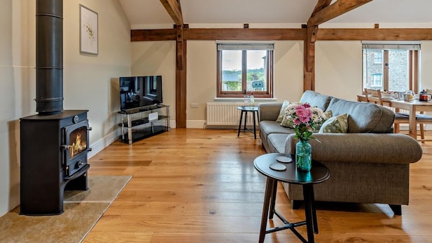 A living room with a fireplace, a sofa, a TV, and a dining area with a view. - 1 Bed in Bucknell (oc-94661) (Letton)