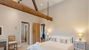A bedroom with a large bed, wooden beams, a desk, and a chair. - 1 Bed in Bucknell (oc-94661) (Letton)