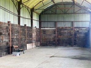 A covered barn interior with a concrete floor, wooden walls, and metal beams. - 1 Bed in Bucknell (oc-94662) (Letton)