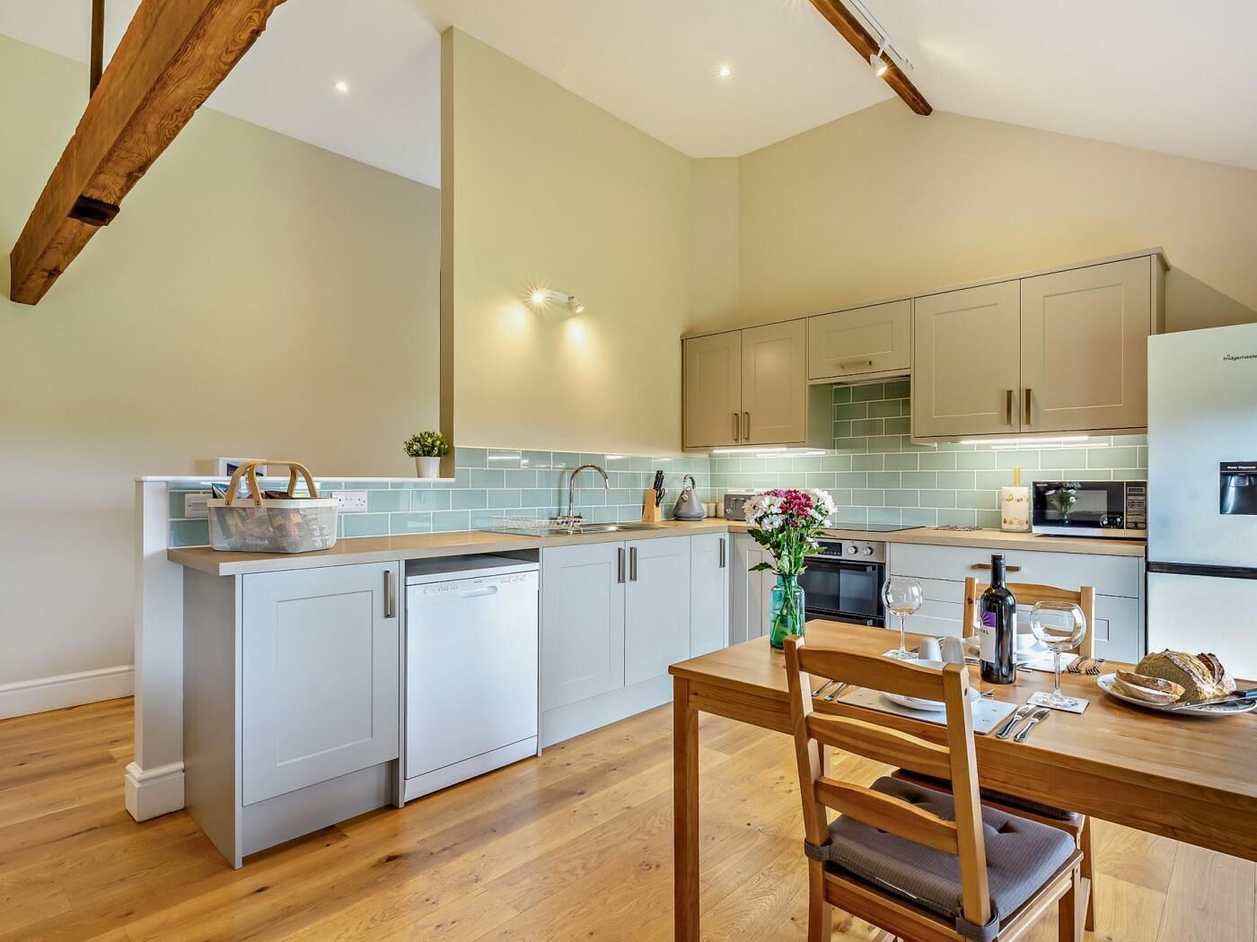 A modern kitchen with a central island, white cabinetry, and a wooden dining table with chairs.