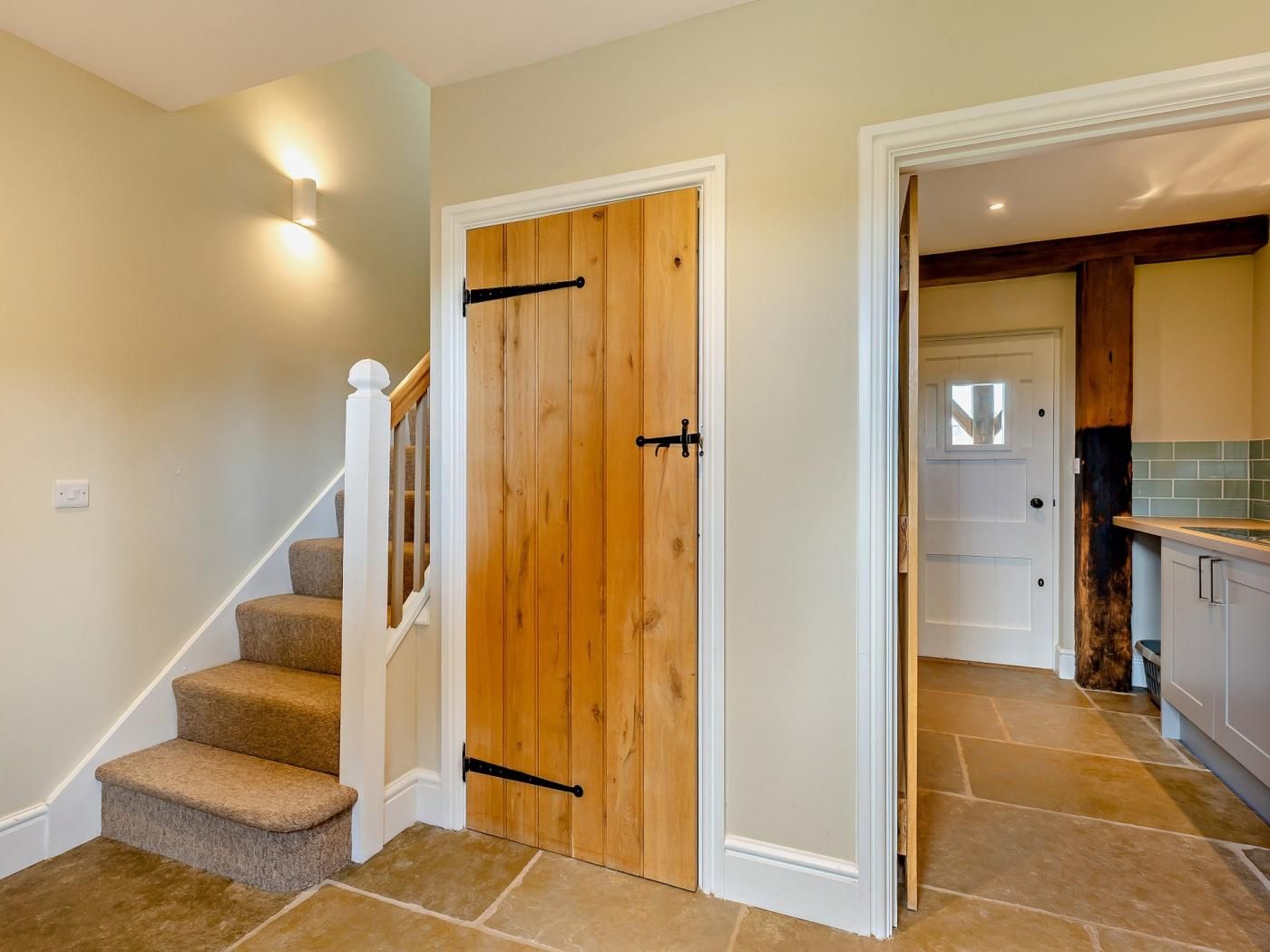 A staircase with carpeted steps leading to a wooden door with a black handle.
