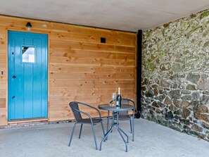 A wooden door with a small window, a stone wall, and a table with chairs outside. - 1 Bed in Bucknell (oc-94662) (Letton)
