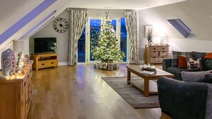 A living room with a TV, a Christmas tree, a sofa, and a wooden cabinet. - 2 Bed in Auchterarder (oc-94546) (Auchterarder)