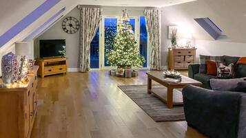 A living room with a TV, a Christmas tree, a sofa, and a wooden cabinet.