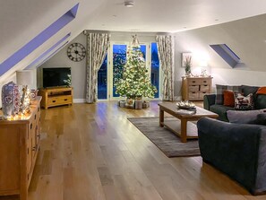 A living room with a TV, a Christmas tree, a sofa, and a wooden cabinet. - 2 Bed in Auchterarder (oc-94546) (Auchterarder)