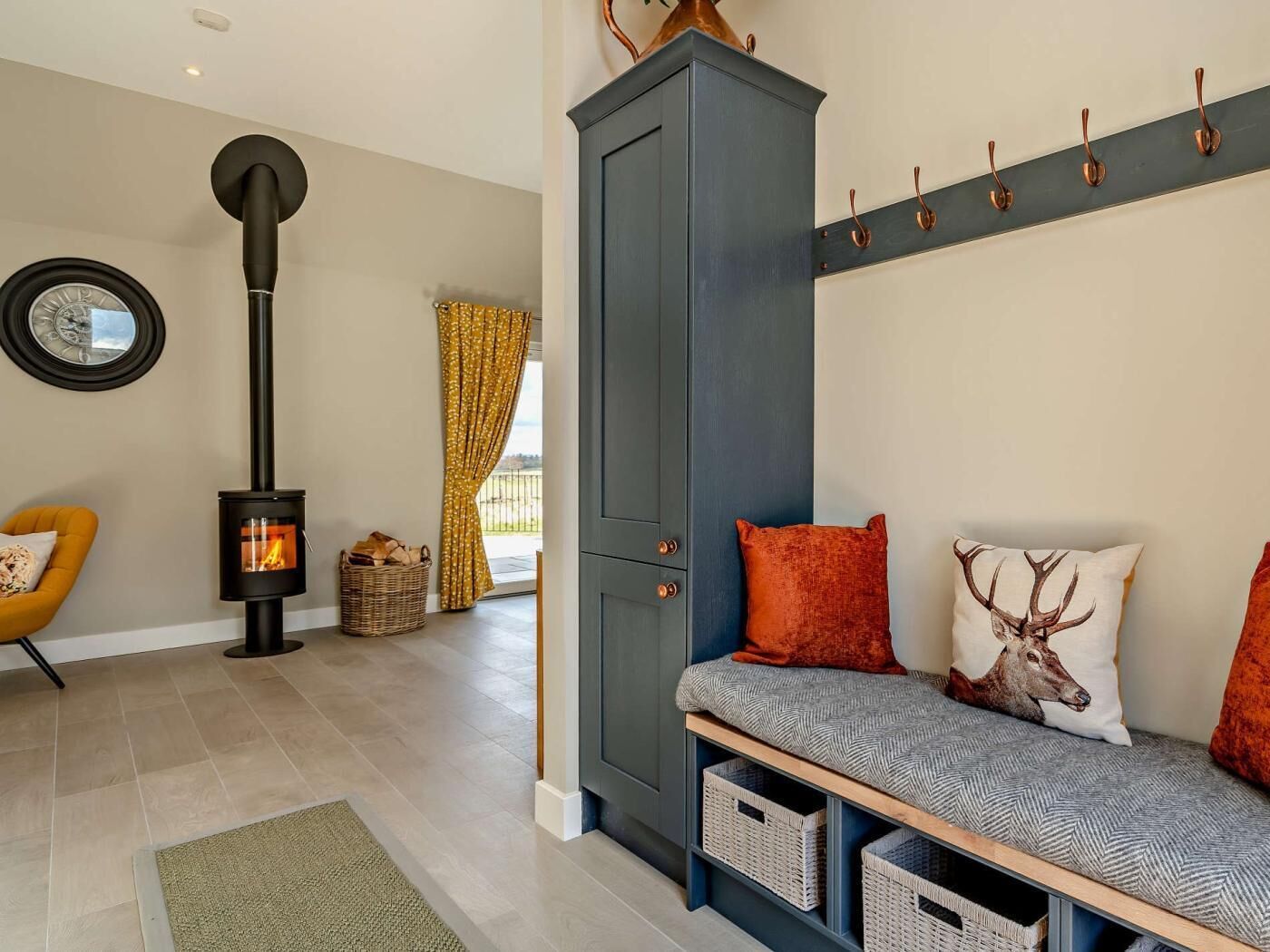 A cozy living room with a fireplace, a sofa with cushions, a cabinet, and a wall-mounted coat rack.