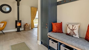 A cozy living room with a fireplace, a sofa with cushions, a cabinet, and a wall-mounted coat rack. - 2 Bed in Auchterarder (oc-94546) (Auchterarder)