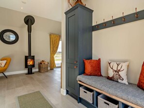 A cozy living room with a fireplace, a sofa with cushions, a cabinet, and a wall-mounted coat rack. - 2 Bed in Auchterarder (oc-94546) (Auchterarder)