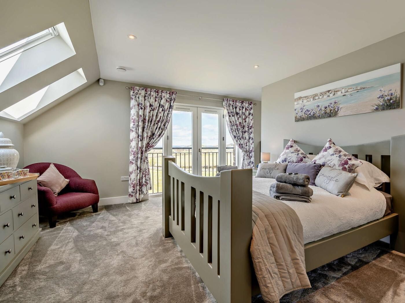 A bedroom with a bed, a dresser, a chair, a window, and a balcony.