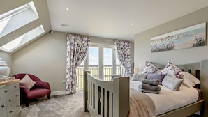 A bedroom with a bed, a dresser, a chair, a window, and a balcony. - 2 Bed in Auchterarder (oc-94546) (Auchterarder)