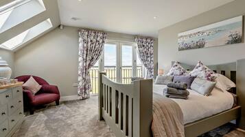 A bedroom with a bed, a dresser, a chair, a window, and a balcony.