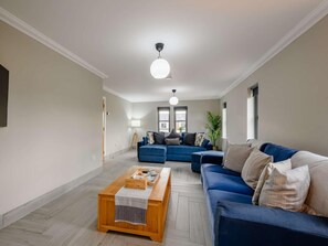 Ein modernes Wohnzimmer mit einem blauen Sofa, einem Holztisch und einer Lampe.