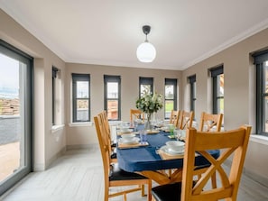 A dining room with a table set for six, large windows, and a ceiling light. - 3 Bed in Alexandria (oc-88753) (Balloch)