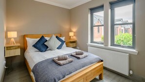 Une chambre à coucher avec un lit, des lampes de chevet, une fenêtre donnant sur un paysage agréable et un radiateur.