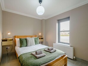Une chambre à coucher avec un lit, des lampes de chevet, une fenêtre et un radiateur.