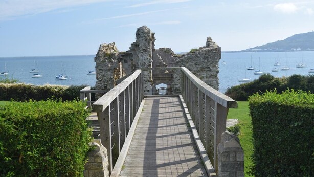A stone pathway leading to a historic stone structure with a view of the sea and boats. - 8 Bed in Bridport (oc-53172) (South Poorton)