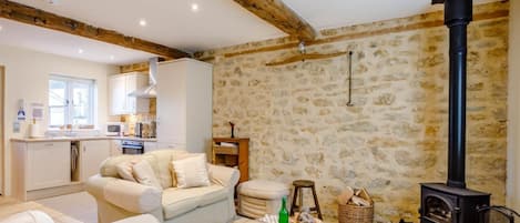 Una sala de estar acogedora con una pared de piedra, una chimenea y un sofá.