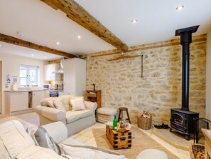 A cozy living room with a stone wall, a fireplace, and a sofa. - 2 Bed in Bridport (oc-dc081) (Bothenhampton)