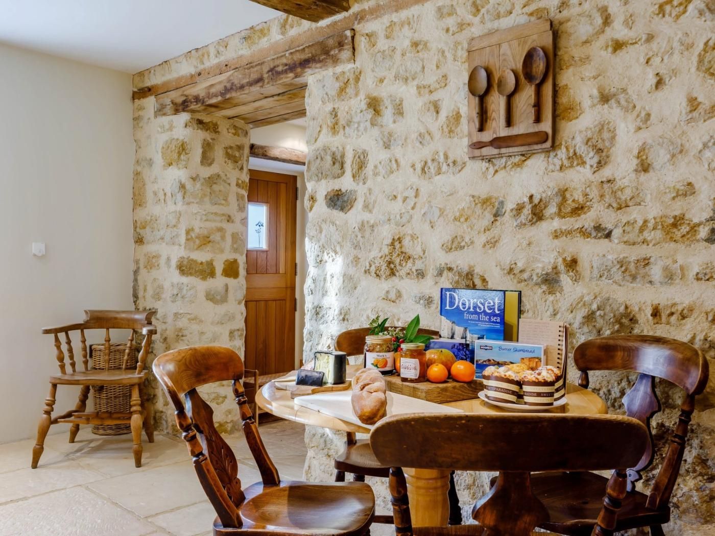 A rustic dining area with stone walls, wooden furniture, and a variety of food items on the table.