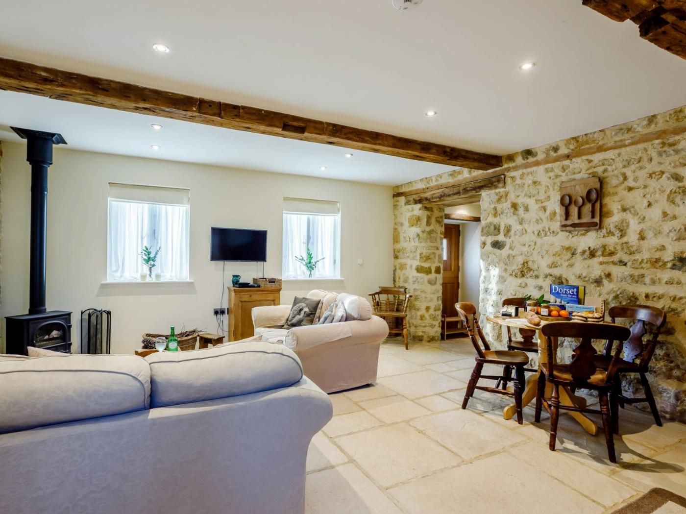 Una sala de estar con un sofá, televisión, chimenea y una pared de piedra.