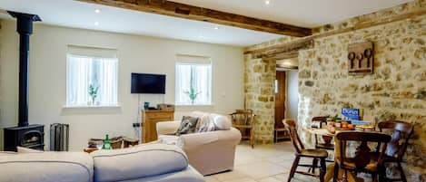 Una sala de estar con un sofá, televisión, chimenea y una pared de piedra.