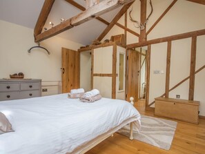 A bedroom with a wooden ceiling, a bed with white bedding, a dresser, and a mirror. - 2 Bed in Bridport (oc-dc081) (Bothenhampton)
