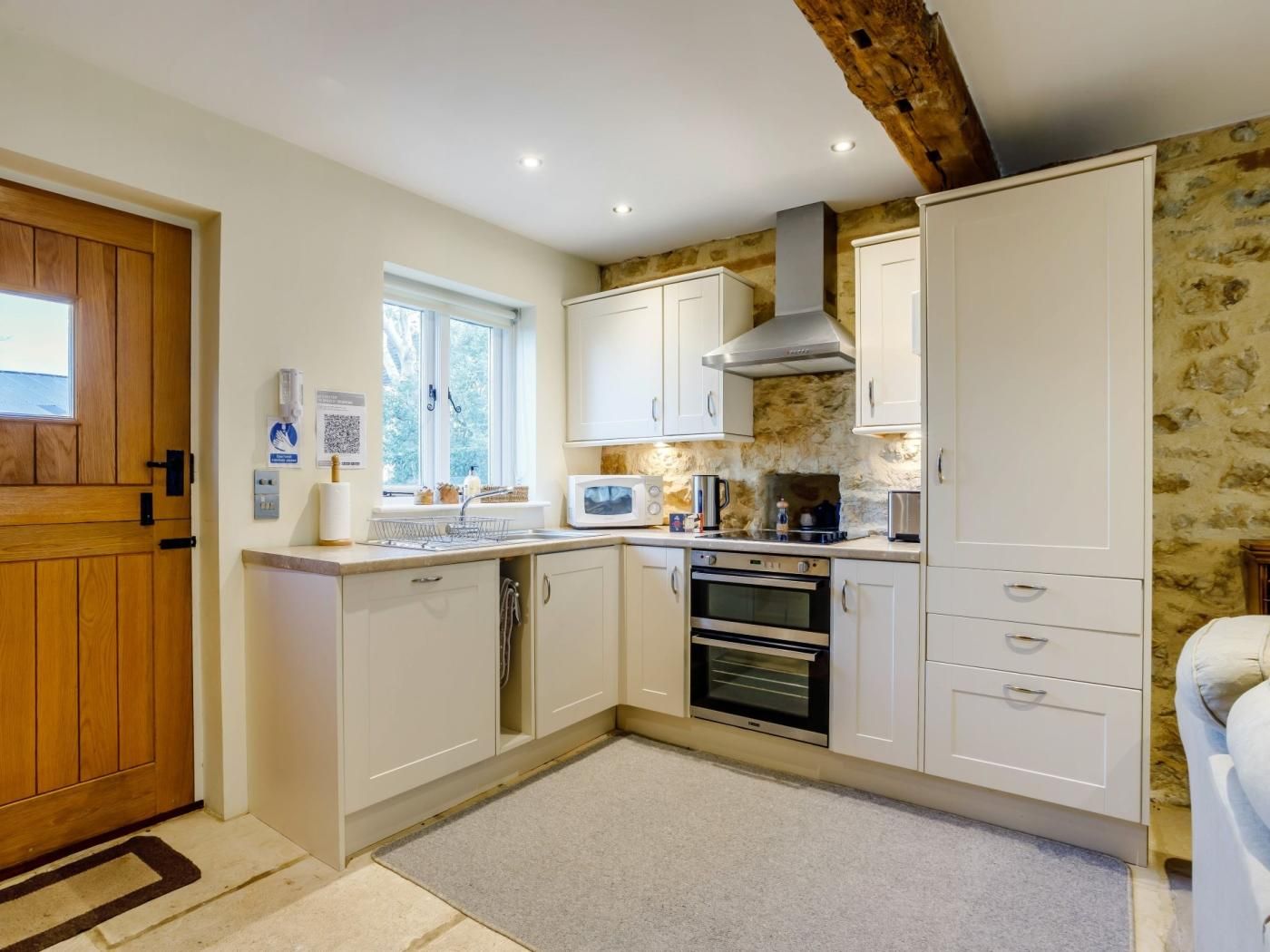 A compact kitchen with white cabinets, a built-in oven, and a window.