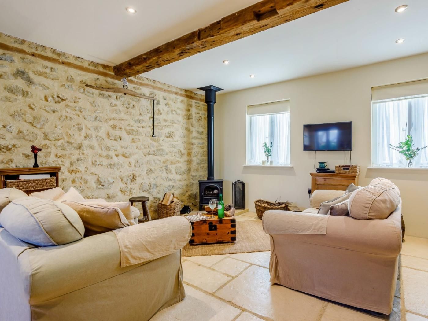 A cozy living room with stone walls, a fireplace, a television, and comfortable seating.