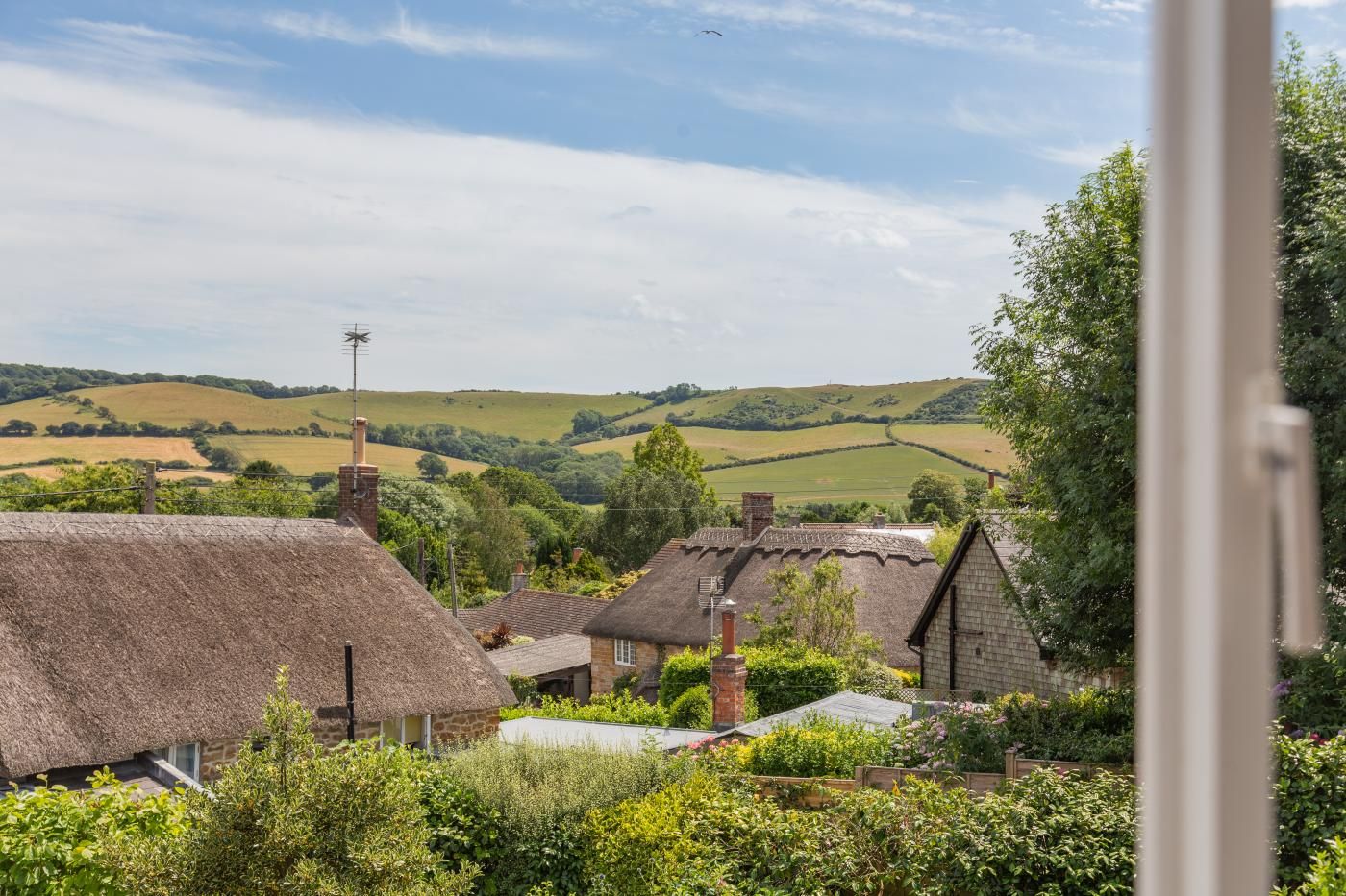 A rural village with thatched-roof cottages and a view of rolling hills.