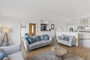Ein modernes Wohnzimmer mit zwei grauen Sofas, einem Couchtisch und einer Lampe.