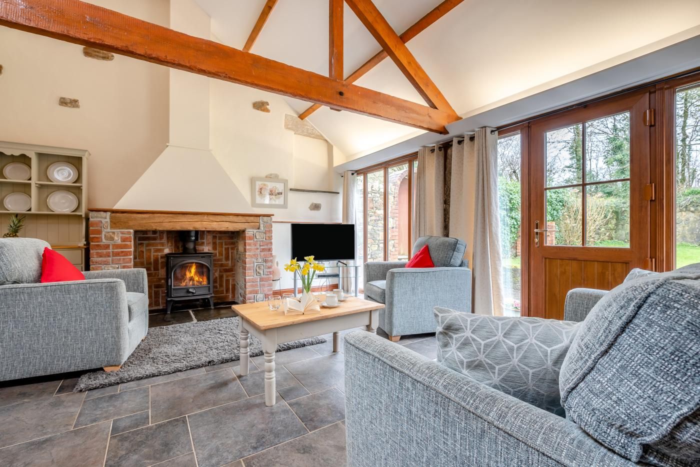 A living room with a fireplace, two grey sofas, a coffee table, and a television.