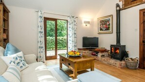 Ein gemütliches Wohnzimmer mit einer Couch, einem Fernseher, einem Kamin und einem Esstisch mit Obst.