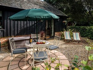 A patio with a table and chairs, a green umbrella, and a bottle of wine. - 1 Bed in North Gorley (oc-nfl59) (Ellingham, Harbridge and Ibsley)