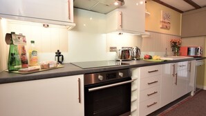 A modern kitchen with stainless steel appliances, white cabinetry, and a black countertop. - 2 Bed in Holt (oc-73335) (Holt)