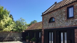 A traditional stone building with a tiled roof, a stone wall, and potted plants. - 2 Bed in Holt (oc-73335) (Holt)