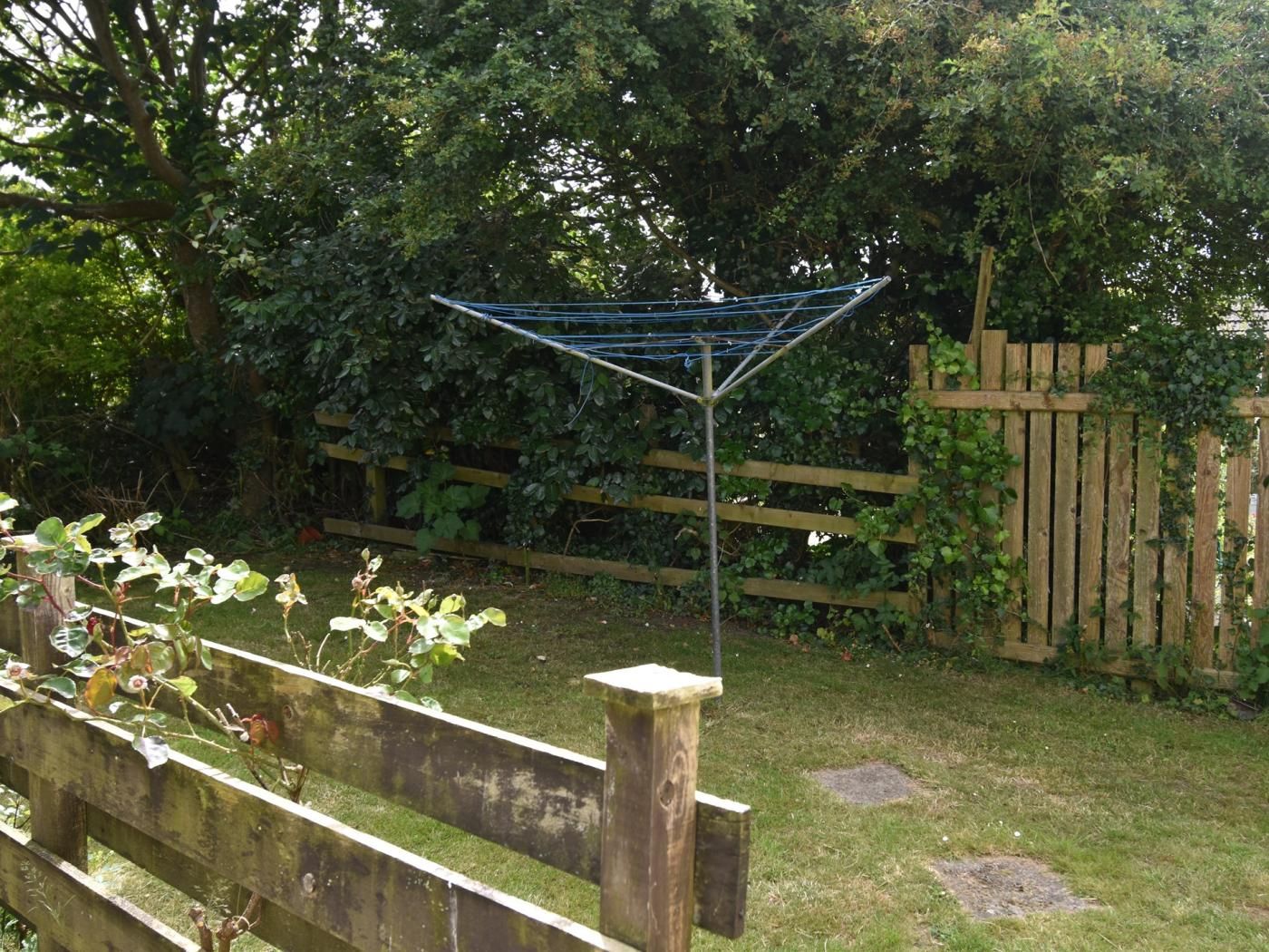 Ein Garten mit einer Wäscheleine an einem Holenzaun.