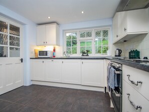 A modern kitchen with white cabinets, a built-in oven, and a window with a view of greenery. - 2 Bed in Wareham (oc-dc093) (West Lulworth)