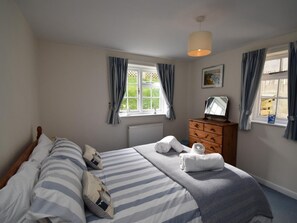 A bedroom with a bed, a dresser, a window with curtains, and a hanging light fixture. - 2 Bed in Wareham (oc-dc093) (West Lulworth)