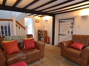 A living room with two leather sofas, a bookshelf, and a staircase leading to an upper floor. - 2 Bed in Wareham (oc-dc093) (West Lulworth)