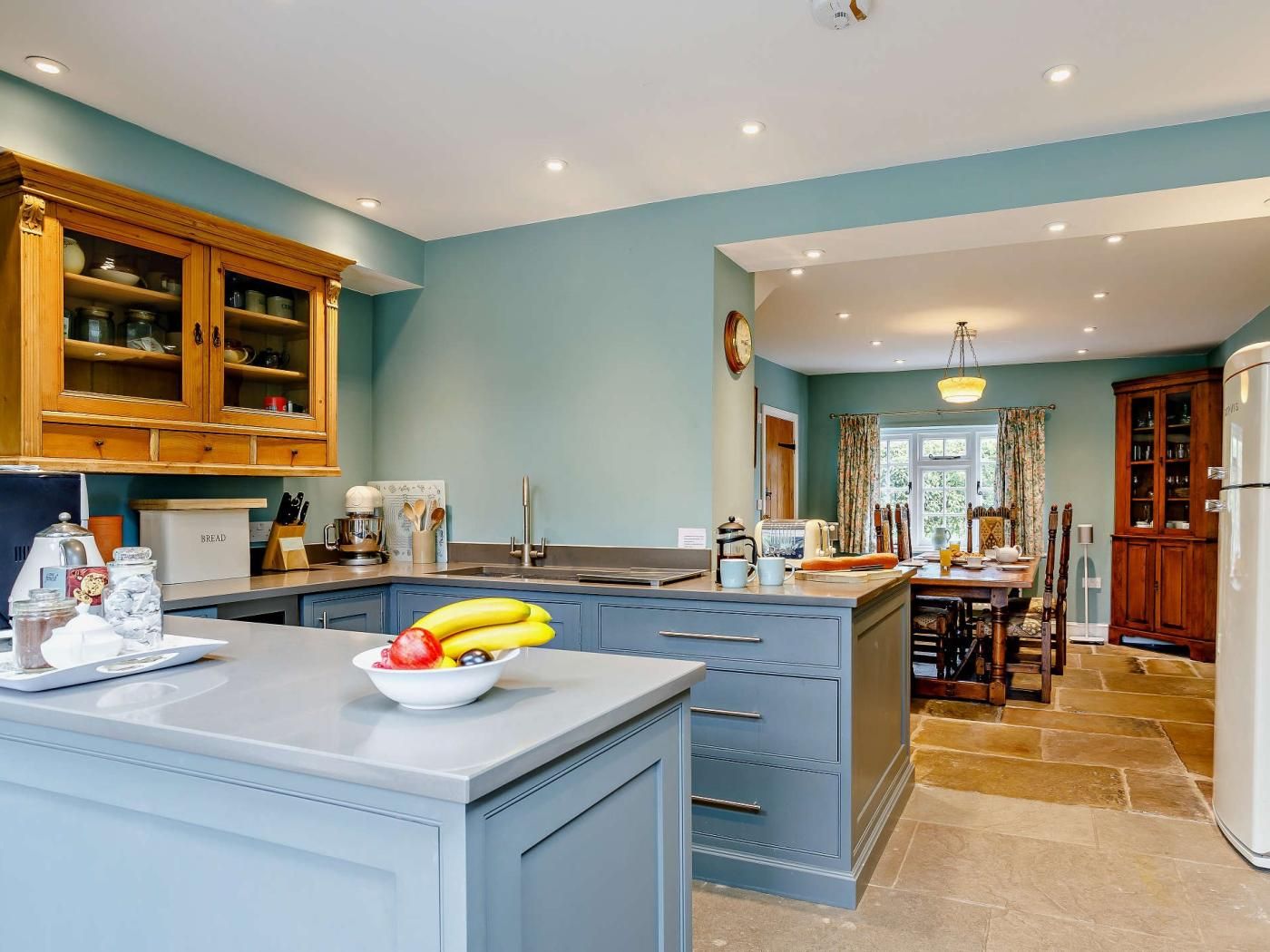A kitchen with a central island, wooden cabinets, and a dining area with a table and chairs.