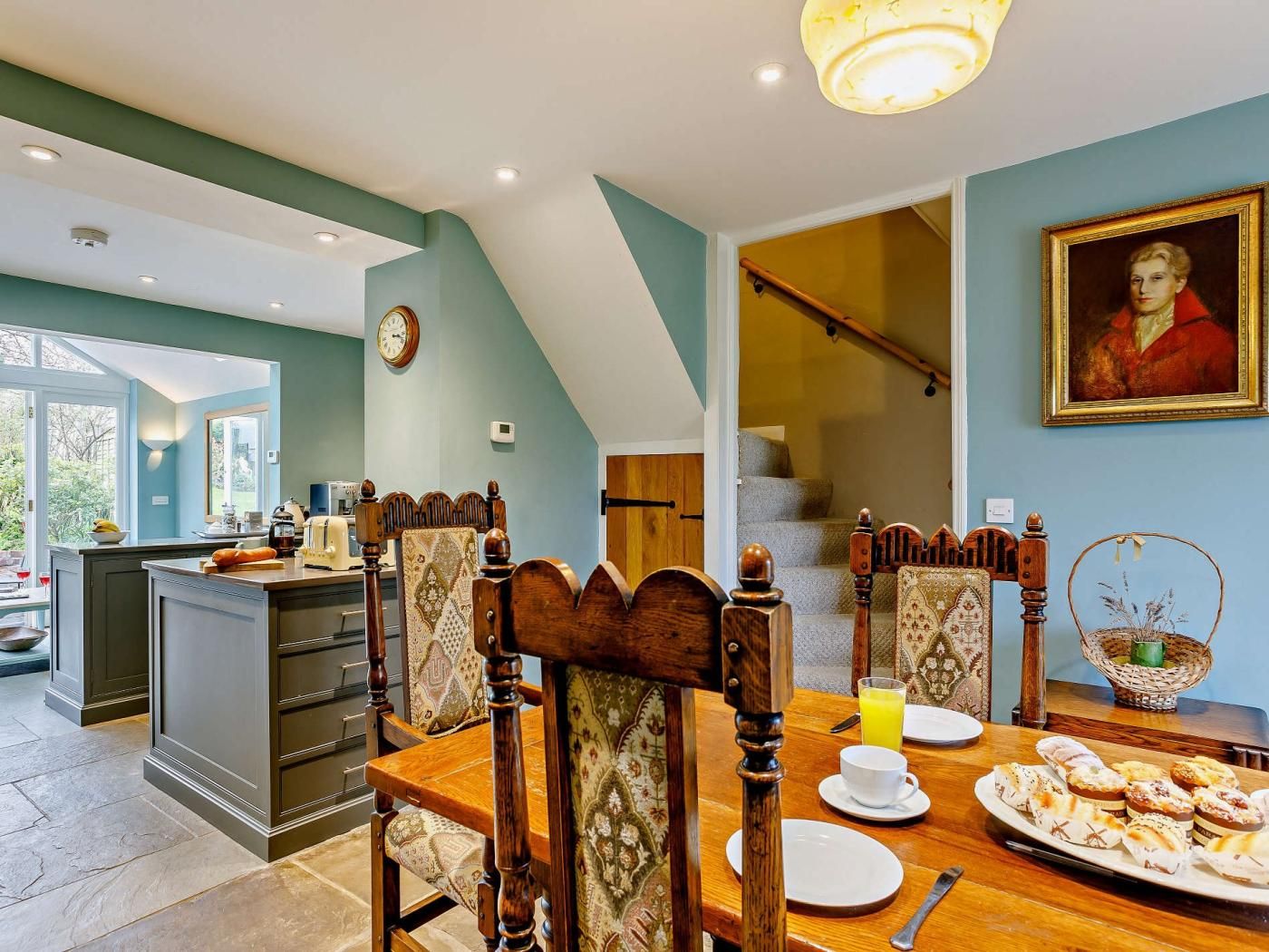 A dining area with a wooden table, chairs, and a breakfast spread.
