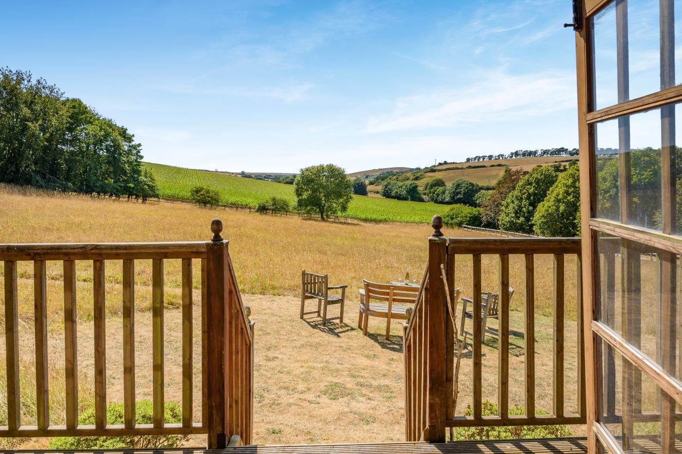 Eine Holzterrasse mit Blick auf einen Weinberg und sanfte Hügel.