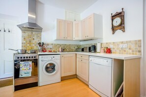 A compact kitchen with a stove, washing machine, dishwasher, and a clock on the wall. - 1 Bed in Dorchester (oc-dc092) (Winfrith Newburgh)